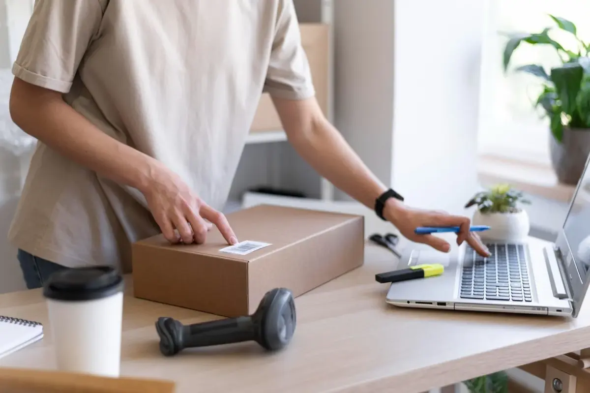 Người bán hàng đóng gói đơn hàng bên máy tính xách tay